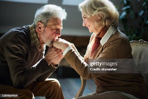 romantic senior man kissing his wife's hands at home. - kissing hand stock pictures, royalty-free photos & images