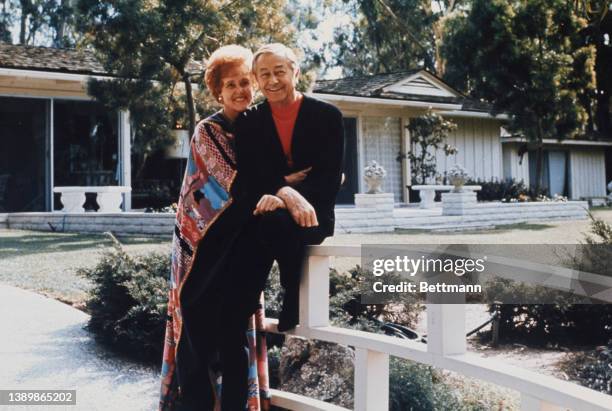 Betty Henderson hugs her husband, American actor Robert Young , who sits on a balustrade in the garden of their home in Beverly Hills, California,...