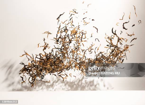 black tea leaves flying on white background - feuilles-de-thé-séchées photos et images de collection