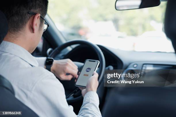 a ride-hailing driver is looking at his smart watch to check the time - asian and indian ethnicities smartwatch phone stock pictures, royalty-free photos & images