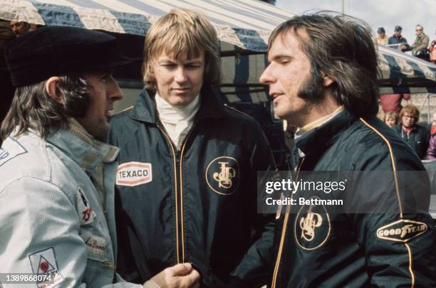 British racing driver Jackie Stewart in conversation with Swedish racing driver Ronnie Peterson and Brazilian racing driver Emerson Fittipaldi, both...