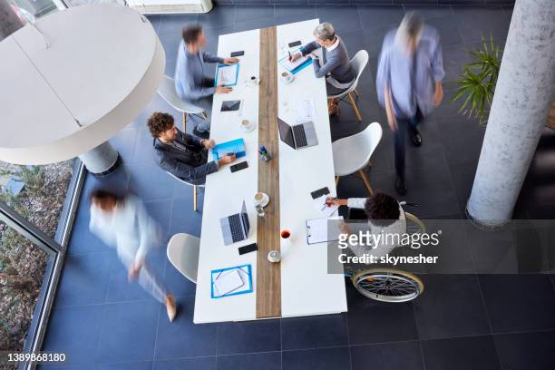 above view of entrepreneurs working at conference table in the office. blurred motion. - weakness stock pictures, royalty-free photos & images