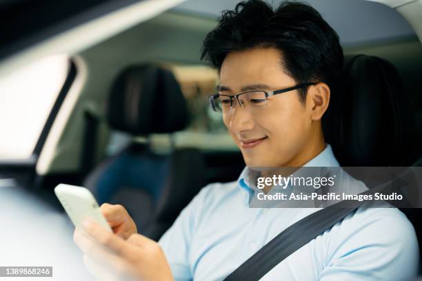 young asian man  using smart phone and enjoying new car. - audi man stockfoto's en -beelden