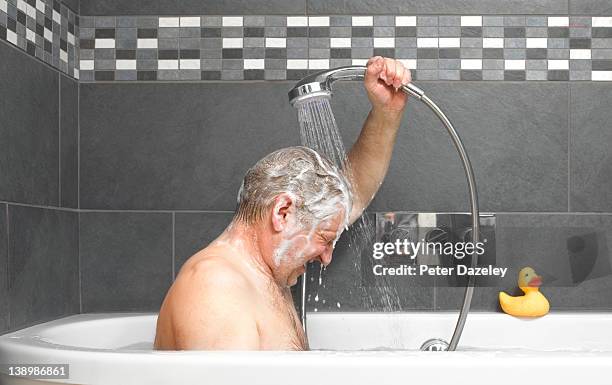 active senior washing in bath - douche photos et images de collection