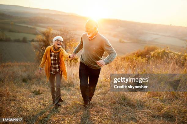 carefree mature couple having fun in autumn day at sunset. - autumn sunsets stock pictures, royalty-free photos & images