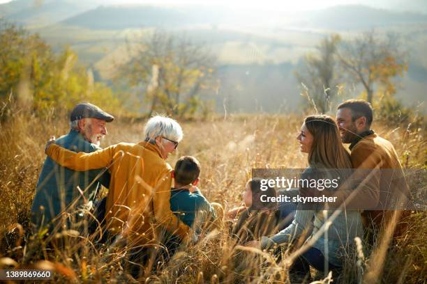 happy multi-generation family talking in autumn day on a hill. - multi generation family from behind stock pictures, royalty-free photos & images