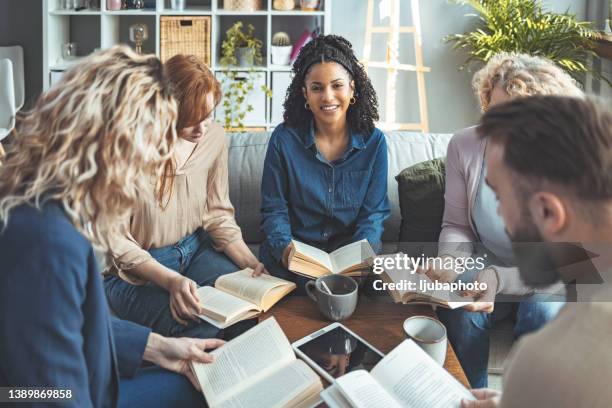 small group of people with a mixed age range talking and laughing while having a book club meeting - book club meeting stockfoto's en -beelden