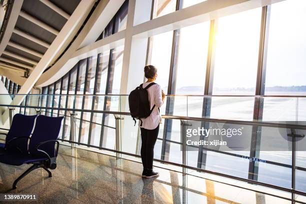 asian young woman waiting for the flight at window of the airport - airport terminal stock pictures, royalty-free photos & images