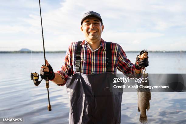 happy fsherman holding large fish - portrait fisherman stock-fotos und bilder