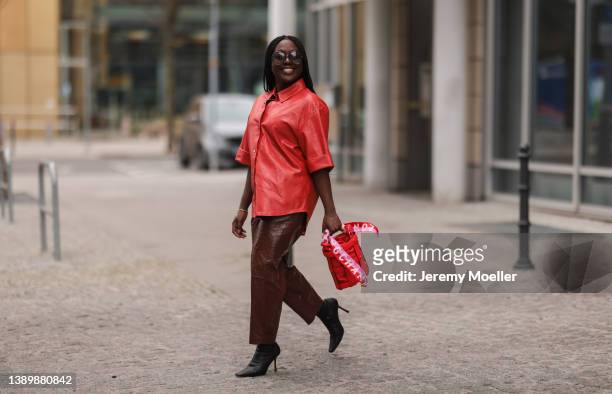 Lois Opoku seen wearing a sunglasses from Pomelato, a red leather shirt blouse from Karl Lagerfeld, a brown leather straight leg pants from Samsoe...