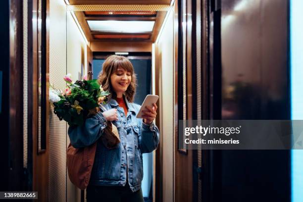 lächelnde frau mit ihrem handy im aufzug - lift stock-fotos und bilder