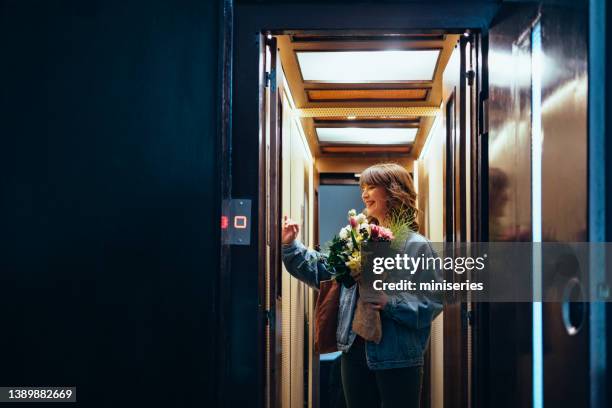 smiling woman with flowers in the elevator - dark floral stockfoto's en -beelden