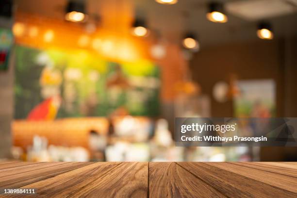 wood table top on blurred of counter cafe shop with light bulb.background - terrasse bar stock-fotos und bilder