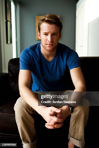 a man sitting on a couch. - handsome man serious tshirt stock-fotos und bilder