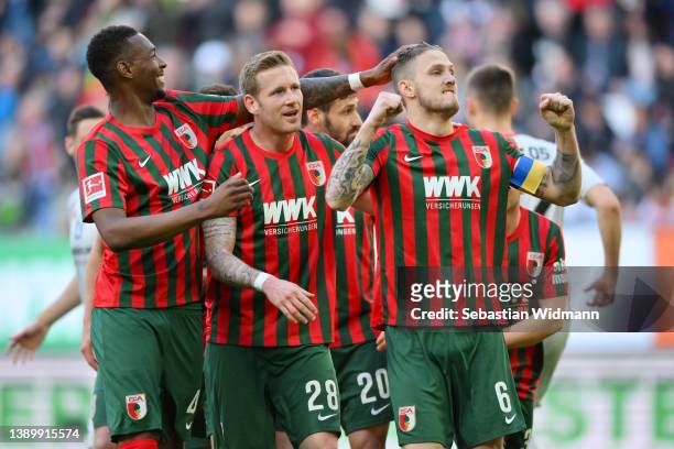 Jeffrey Gouweleeuw of FC Augsburg celebrates with teammates after scoring their team's first goal from the penalty spot during the Bundesliga match...