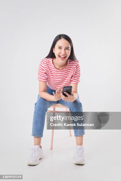 woman sitting on chair and using smart phone - woman excited sitting chair stock pictures, royalty-free photos & images