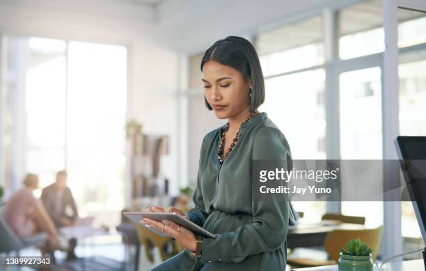 foto de una joven empresaria usando una tableta digital en una oficina moderna - utilizar o tablet fotografías e imágenes de stock