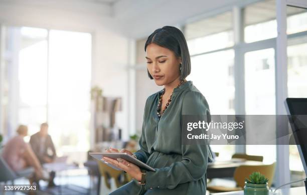 shot of a young businesswoman using a digital tablet in a modern office - corporate business people stock pictures, royalty-free photos & images