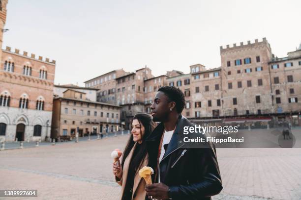 Young adult couple walking in Siena with an ice-cream