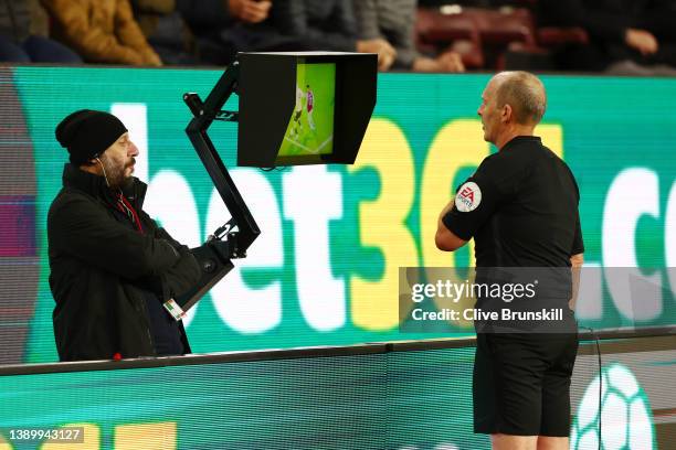 Match referee Mike Dean checks the VAR screen during the Premier League match between Burnley and Everton at Turf Moor on April 06, 2022 in Burnley,...