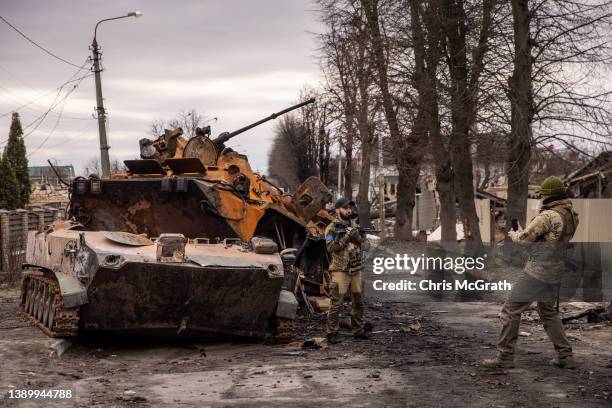 Members of the Ukrainian military take a photograph in front of destroyed Russian military vehicles on a street on April 06, 2022 in Bucha, Ukraine....