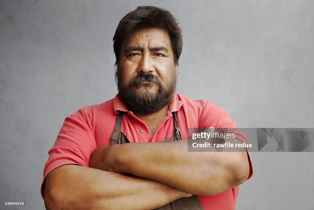 Middle age mexican man with arms crossed.