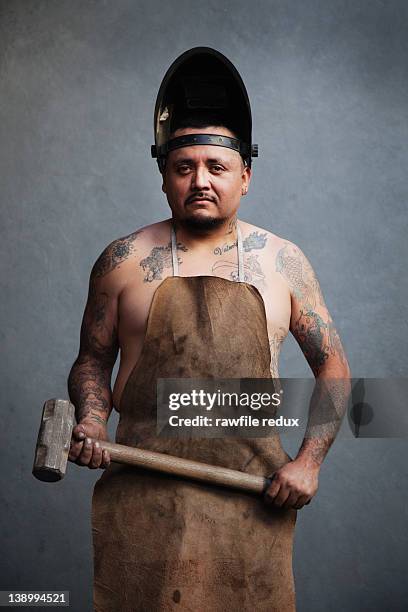 tatooed iron worker holding a hammer. - martillo herramienta de mano fotografías e imágenes de stock