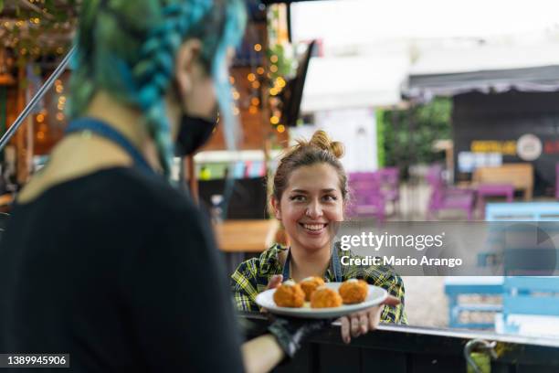 chef of a food truck delivers a plate of food to the waitress - waitress booth stock pictures, royalty-free photos & images