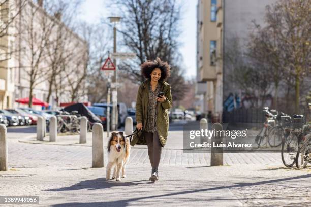 young woman with phone taking her dog out for a walk - animal call fotografías e imágenes de stock