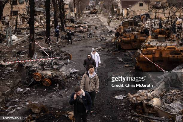 People walk through debris and destroyed Russian military vehicles on a street on April 06, 2022 in Bucha, Ukraine. The Ukrainian government has...