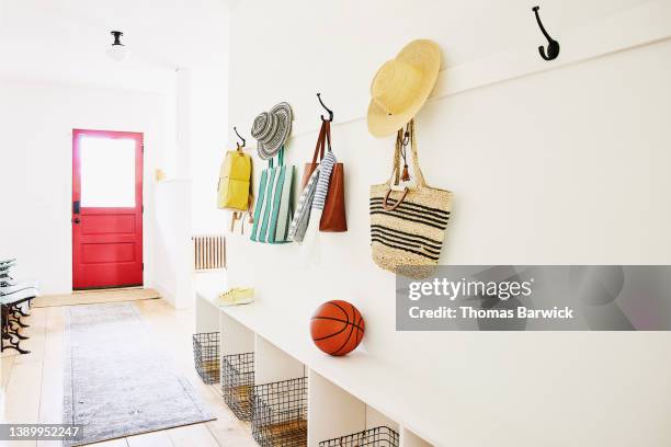 wide shot of bags and hats on hooks in entryway of home - basketball bench stock pictures, royalty-free photos & images