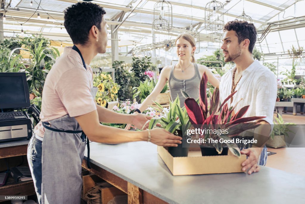 Cashier helping customers at checkout at plant nursery