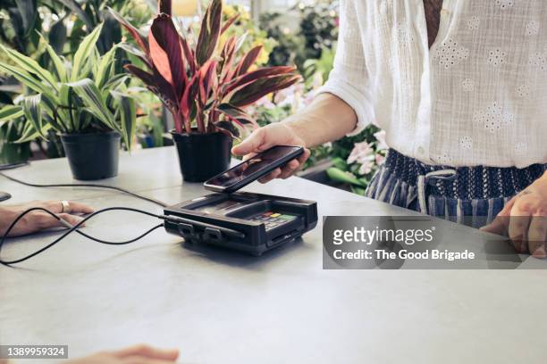 close up of man making contactless payment with mobile phone - close up counter stock pictures, royalty-free photos & images