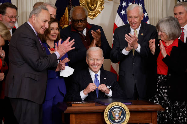 President Joe Biden signs the Postal Service Reform Act into law during an event with Sen. Gary Peters , Senate Majority Leader Charles Schumer ,...