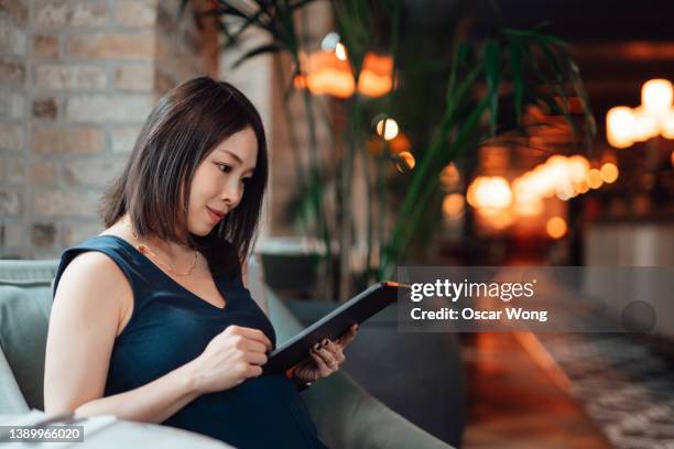 young asian woman using digital tablet at cafe - asian receptionist stock pictures, royalty-free photos & images