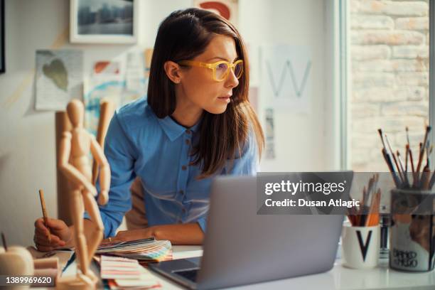 young woman designer working in her home studio - graphic designer stock pictures, royalty-free photos & images