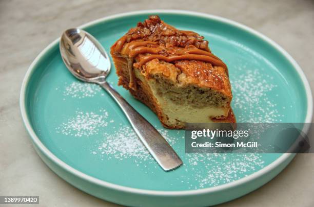 slice of banana and cream cheese bundt cake, topped with pecans and caramel icing, on a plate - ciambellone foto e immagini stock
