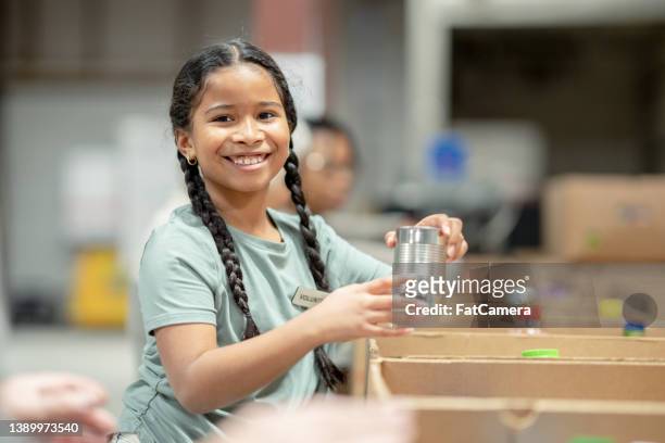 young girl helping pack at a food bank - only girls stock pictures, royalty-free photos & images