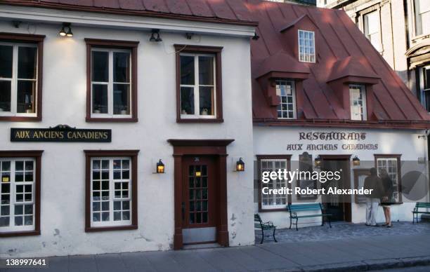 Couple studies the menu posted in front of a French restaurant, built as a home in the 17th Century in historic Old Quebec . The Restaurant Aux...