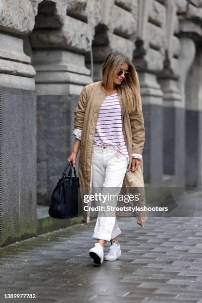 Influencer Gitta Banko wearing a beige coat by G-Lab, a white t-shirt with red stripes by J.Crew, white denim jeans pants by Marni, white sneaker by...