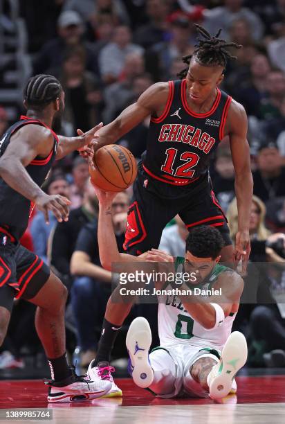 Patrick Williams and Ayo Dosunmu of the Chicago Bulls knock the ball away from Jayson Tatum of the Boston Celtics at the United Center on April 06,...