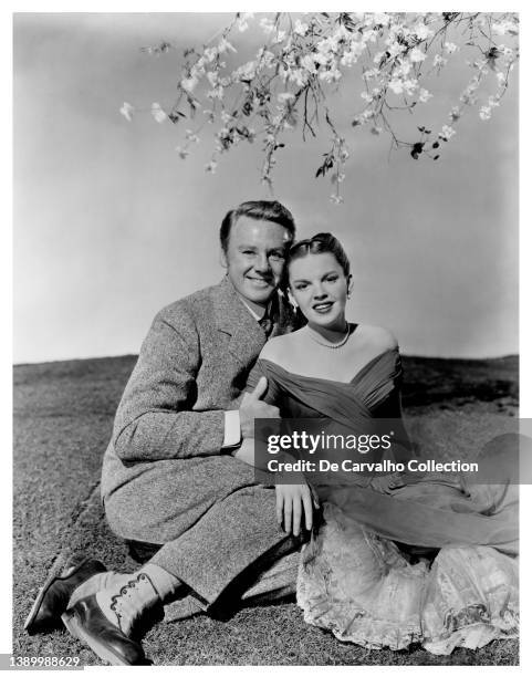 Actor Van Johnson as 'Andrew Delby Larkin' and Actress Judy Garland as 'Veronica Fisher' sit on the grass under a blossoming tree in a publicity shot...