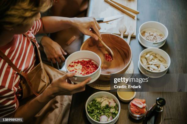 wochenendaktivität eines asiatischen schwulen paares, das gemeinsam thailändischen salat zum mittagessen kocht. - thai food stock-fotos und bilder