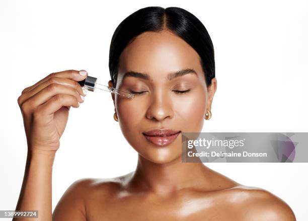 foto de estudio de una atractiva joven que se aplica suero en la cara sobre un fondo blanco - cuentagotas fotografías e imágenes de stock