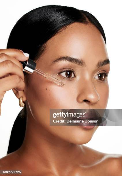 studio shot of an attractive young woman applying serum to her face against a white background - face oil stock pictures, royalty-free photos & images
