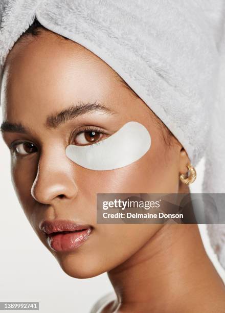 studio shot of an attractive young woman wearing an under eye patch against a white background - medical eye patch stockfoto's en -beelden