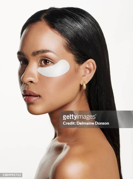 studio shot of an attractive young woman wearing an under eye patch against a white background - medical eye patch stockfoto's en -beelden