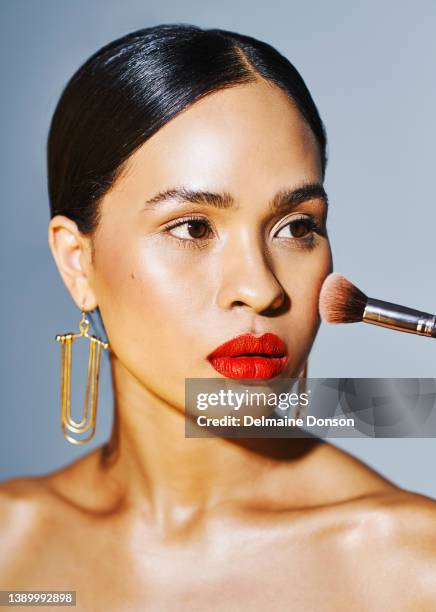 studio shot of an attractive young woman applying makeup against grey background - woman applying blush stock pictures, royalty-free photos & images