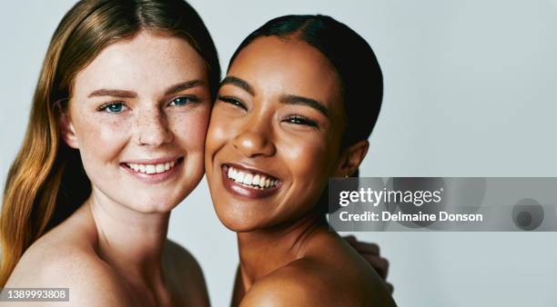 studio shot of two attractive young women posing against grey background - touching face stock pictures, royalty-free photos & images