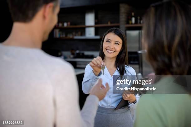 real estate agent giving the keys of their new house to a couple - tenant imagens e fotografias de stock